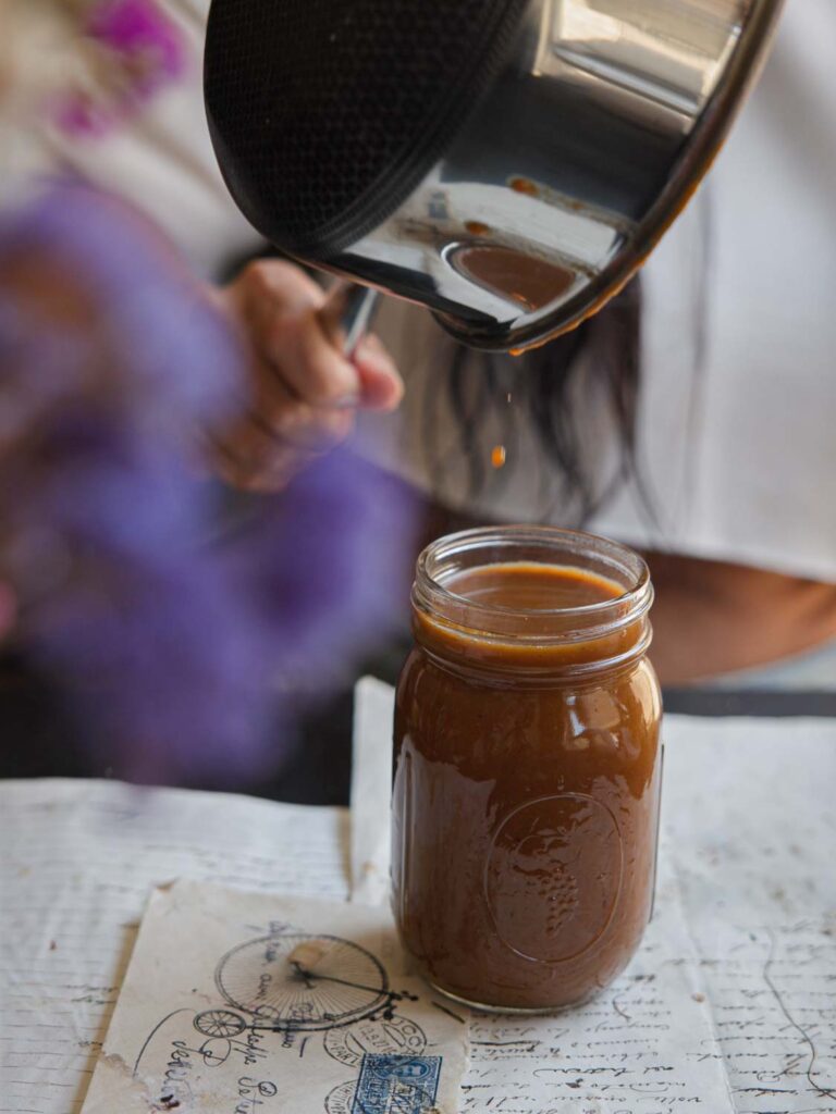 pouring last drops of vegan pumpkin spice syrup into mason jar